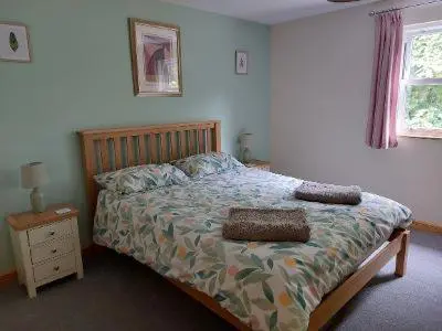 a bedroom with a bed with a wooden headboard and a bed sidx sidx sidx at Two bedroom cottage - country lane -10 min walk to Perranporth beach in Perranporth