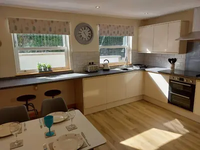 a kitchen with a table and a clock on the wall at Two bedroom cottage - country lane -10 min walk to Perranporth beach in Perranporth