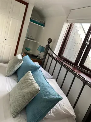a bed with two blue pillows and a window at Meadowview Cottage, St Ives View in Camborne