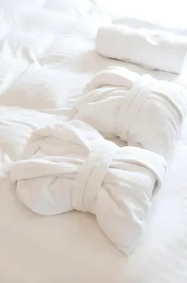 two white towels laying on a white bed at Fistral hot tub house for 8 on Retallack Resort in Newquay