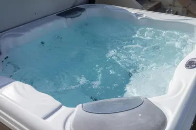 a bath tub with blue water in it at Fistral hot tub house for 8 on Retallack Resort in Newquay