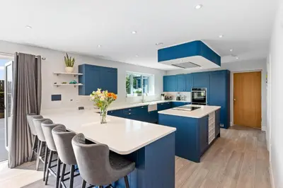 a blue kitchen with a white counter and blue cabinets at Shackled-Am-Not - Luxury home sleeps 8 with hot tub and games room North Cornwall in Camelford