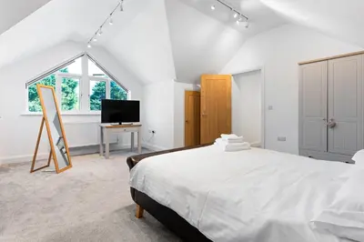 a white bedroom with a bed and a tv at Shackled-Am-Not - Luxury home sleeps 8 with hot tub and games room North Cornwall in Camelford