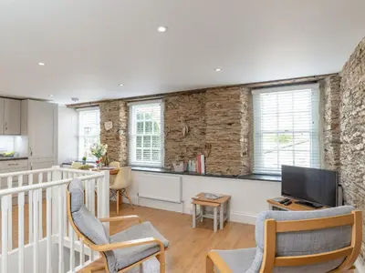 a kitchen and living room with brick walls at Dayan Cottage in Fowey