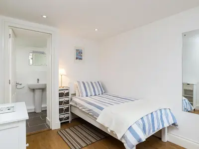 a white bedroom with a bed and a sink at Dayan Cottage in Fowey