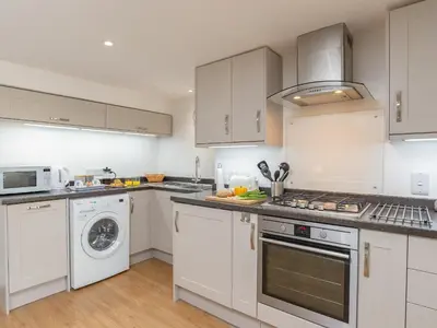 a kitchen with white cabinets and a washer and dryer at Dayan Cottage in Fowey