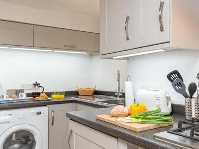 a kitchen with a counter with vegetables on a cutting board at Dayan Cottage in Fowey