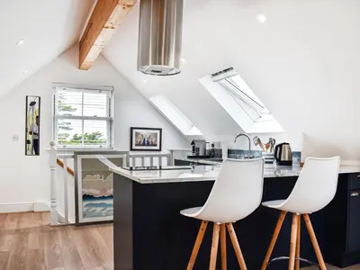 a kitchen with black and white counters and white stools at Elmington Studio in Tintagel