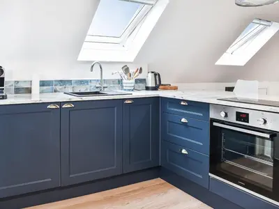 a kitchen with blue cabinets and a sink at Elmington Studio in Tintagel