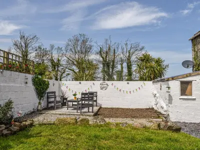 a patio with two chairs and a wall at Bee Cottage in Hayle
