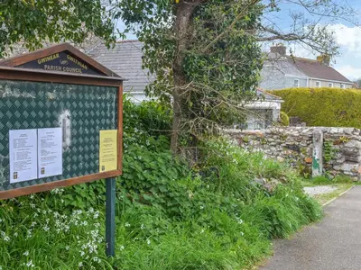 a sign in the grass next to a house at Bee Cottage in Hayle
