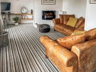 a living room with brown leather couches and a fireplace at The Steps in Pentewan