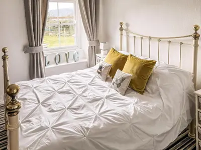 a bed with white sheets and pillows in a bedroom at The Steps in Pentewan