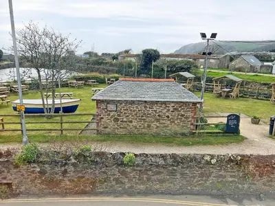 a small brick building with a boat in a field at The Steps in Pentewan