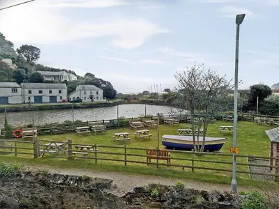 a park with a boat in the grass next to a river at The Steps in Pentewan