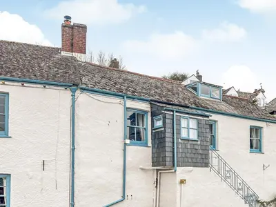 a white house with blue windows and a roof at The Steps in Pentewan