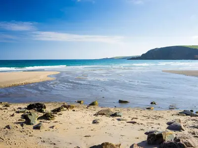 a beach with rocks on the sand and the ocean at The Steps in Pentewan