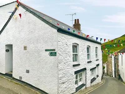 a white building with flags on the side of it at Zion Cottage in St Austell