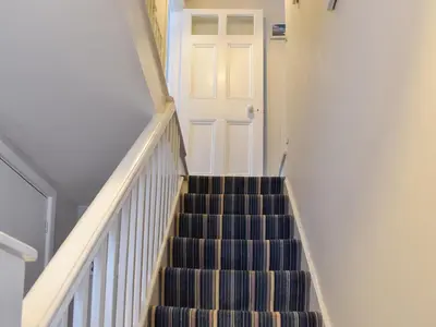 a stairway with a white door and a staircase at Zion Cottage in St Austell