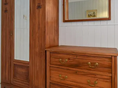 a bathroom with a wooden dresser and a mirror at Zion Cottage in St Austell