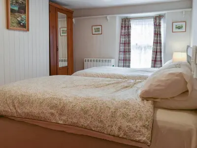 a bedroom with two beds and a window at Zion Cottage in St Austell
