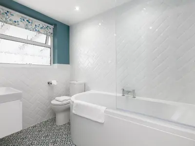 a white bathroom with a tub and a toilet at The Pines in St Ives