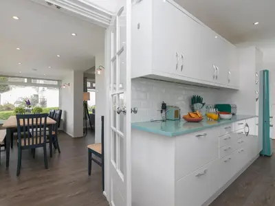 a kitchen with white cabinets and a dining room at The Pines in St Ives