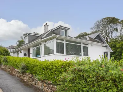 a white house with large windows and bushes at The Pines in St Ives