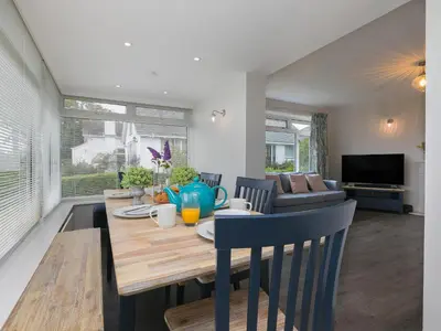 a dining room and living room with a table and chairs at The Pines in St Ives