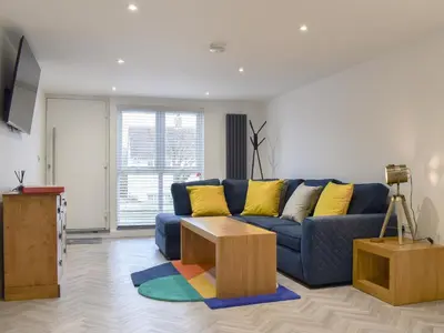a living room with a blue couch and yellow pillows at Little Trevose in Padstow