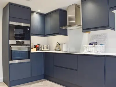 a kitchen with navy blue cabinets and appliances at Little Trevose in Padstow