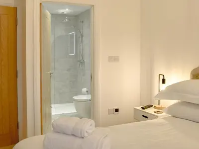 a white bedroom with a shower and a bed with towels at Little Trevose in Padstow
