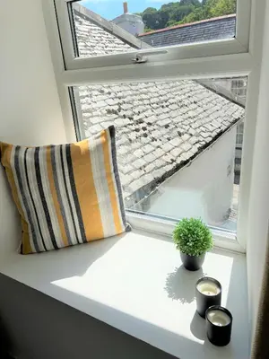 a window sill with a pillow and a potted plant at Your luxurious and secluded retreat in Cornwall in Helston