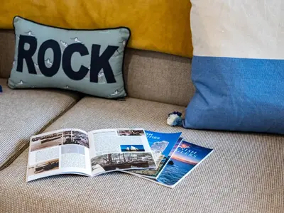 a book and magazines on a couch with a pillow at The Snug in Wadebridge