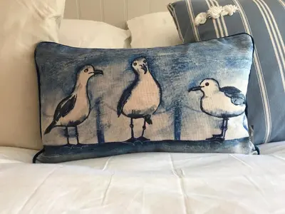 a cushion with four birds on it sitting on a bed at The Snug in Wadebridge