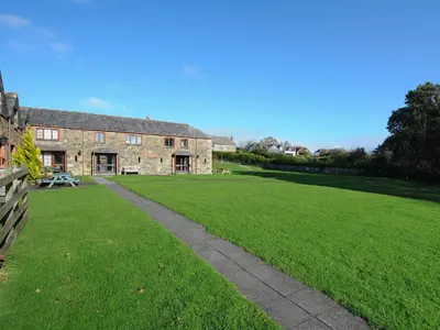 an old stone building with a grass field next to it at The Snug in Wadebridge