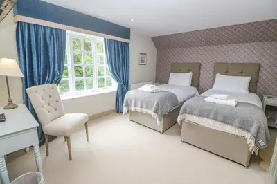 a bedroom with two beds and a chair and a window at Bodmin Country House in Bodmin