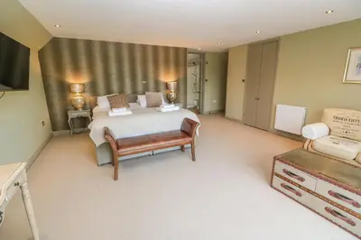 a large bedroom with a bed and a chair at Bodmin Country House in Bodmin