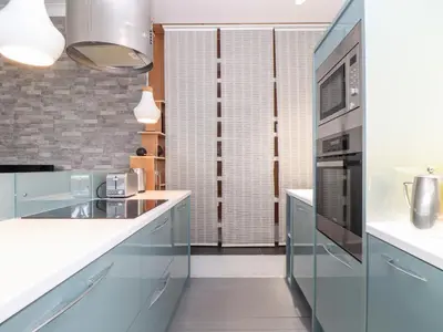 a kitchen with white counters and a microwave at Three Gables in Newquay