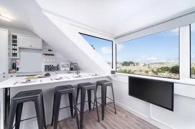 a kitchen with a bar with stools and a large window at Len's Lookout in St Ives