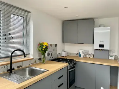 a kitchen with white cabinets and a sink with a vase of flowers at The Little Hideaway in Truro