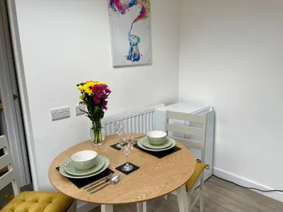 a dining room table with a vase of flowers on it at The Little Hideaway in Truro