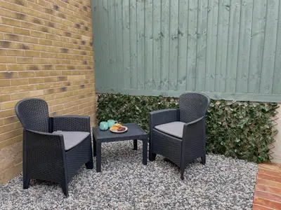 three wicker chairs and a table with a plate on it at The Little Hideaway in Truro