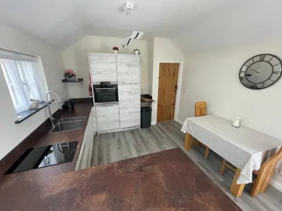 a kitchen with a table and a clock on the wall at Sunnyside Cow Shed one bedroom central Cornwall in Truro