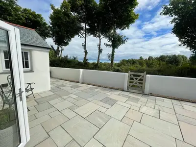 a patio with a white fence and a wooden gate at Sunnyside Cow Shed one bedroom central Cornwall in Truro