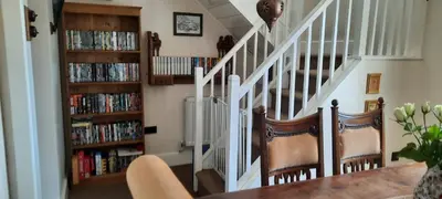 a living room with a staircase with dvds at Trelake Cottage in Tintagel