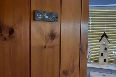a bathroom with a sign on a wooden wall at Trelake Cottage in Tintagel