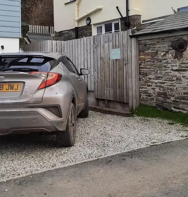 a car parked in front of a wooden fence at Trelake Cottage in Tintagel