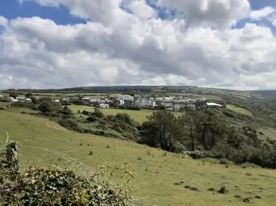 a green field with a town in the distance at Trelake Cottage in Tintagel