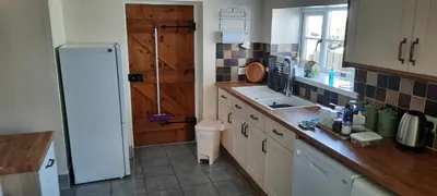 a kitchen with a white refrigerator and a sink at Trelake Cottage in Tintagel